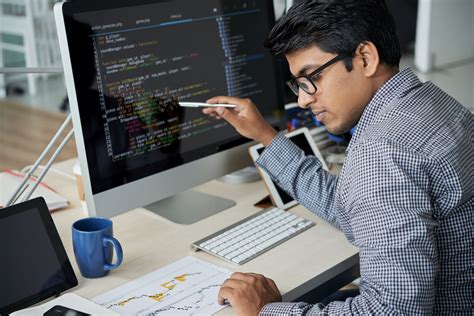 Side view of computer programmer programming on laptop at desk in