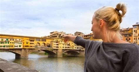 A tour guide pointing out a hidden garden in Florence, full of blooming flowers and hidden arches