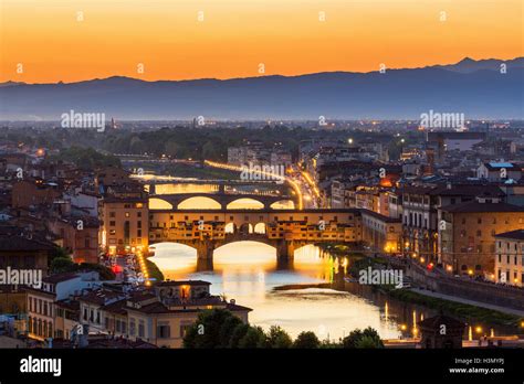 A picturesque sunset view of Ponte Vecchio, with its charming shops and the Arno River flowing beneath it.