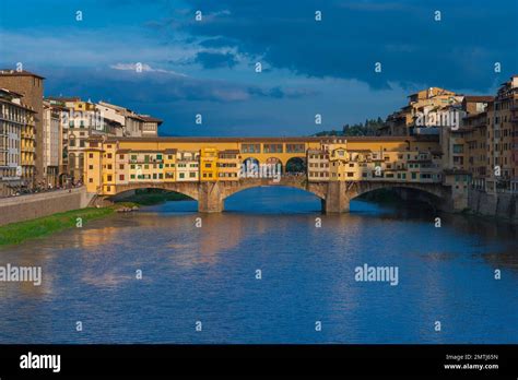 A panoramic view of Florence, showing the iconic Ponte Vecchio bridge, lined with shops and bustling with life.