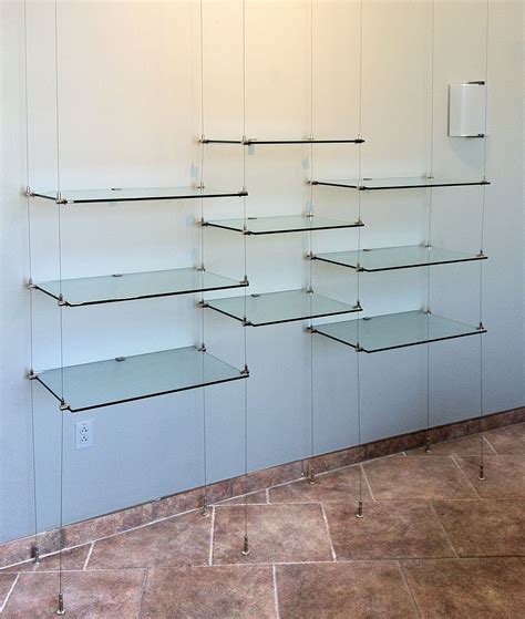 Open ceiling mounted glass and brass shelving in window Amuneal Collector's Shelving Design by