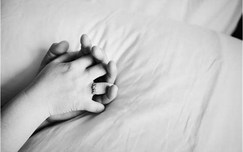 Image Of A Couple In Bed Holding Hands