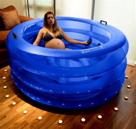 A large birthing pool filled with warm water and a woman floating inside.