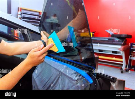 Man Using Squeegee To Apply Window Tint