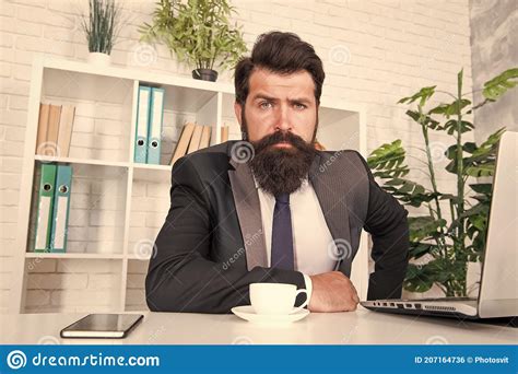 Man with beard and haircut sitting at office desk smiling