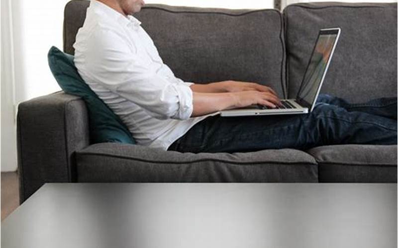 Person Using Laptop While Sitting On Sofa