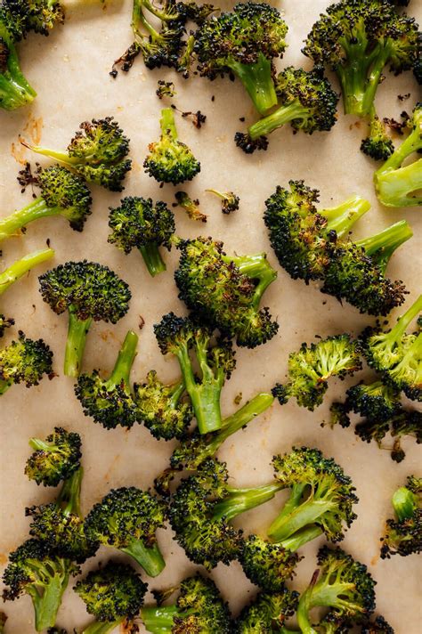 Image of a roasting pan filled with broccoli florets tossed in olive oil and seasonings