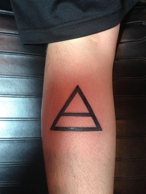 Simple triangle shaped tattoo on forearm stylized with red