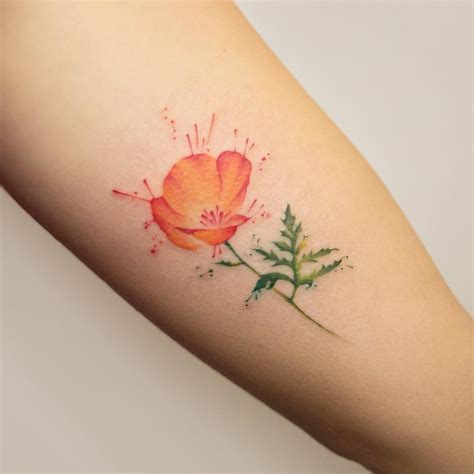 Black watercolor flower tattoo on the left upper arm