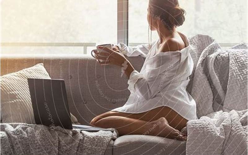 Woman Using Laptop While Sitting On Sofa At Home