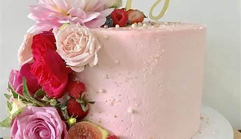 Fiftieth frosted pink birthday cake with fresh flowers and fruit Fresh