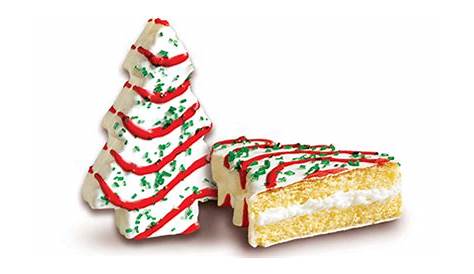 two decorated christmas trees next to a piece of cake on a white