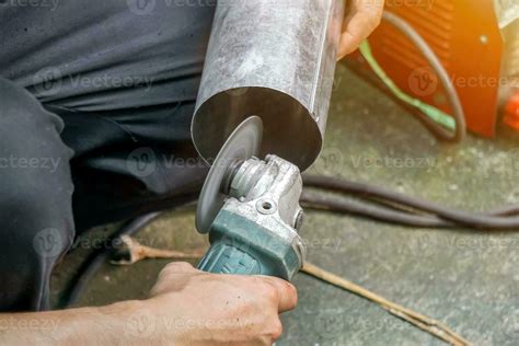 Closeup Hands of Laborer Holding Electric Angle Grinder Working Cutting