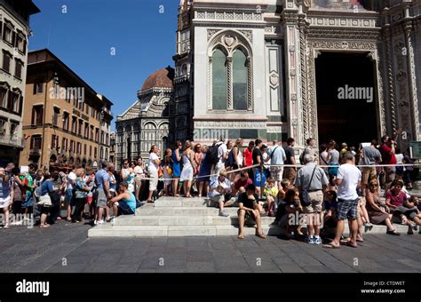 A line of people waiting to enter the Duomo, with the building's facade visible in the background