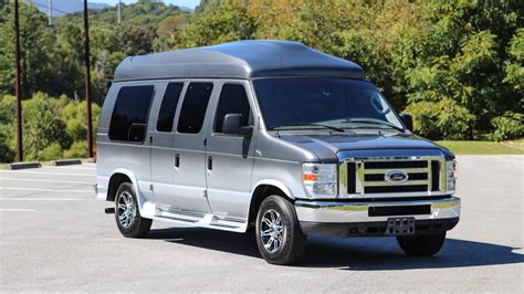 A white Ford conversion van parked outdoors, showcasing its spacious interior potential