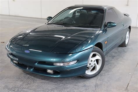 Side profile of a red Ford Probe Automatic parked on a street