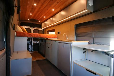 Professionally converted Ford Transit van interior with custom cabinetry and sleeping area