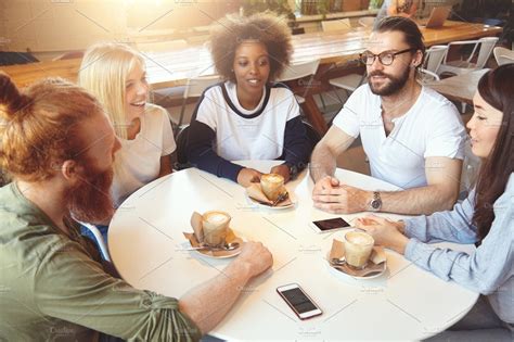 Image of a group of people sitting at a table, talking and smiling