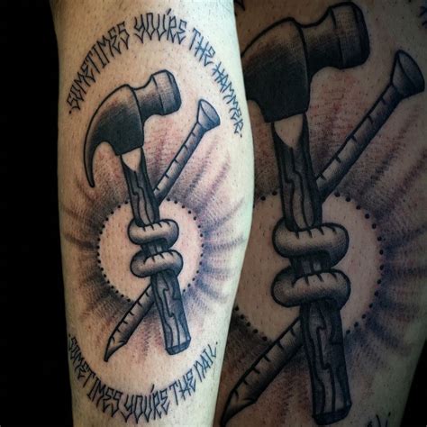 Crossed hammer and nail tattoo on shoulder in engraving style