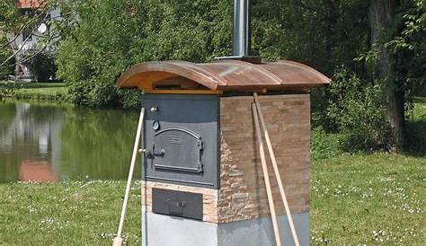 a man standing next to a yellow birdhouse with a pizza in it's oven