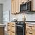 light wood kitchen cabinets with black appliances