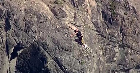 man clinging to a cliff rescued