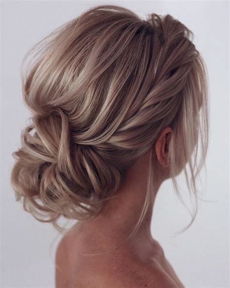curly wedding hairstyles textured messy low bun with accessories and
