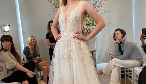 a woman standing in front of some wedding dresses