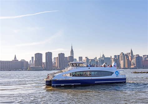 A modern NYC Ferry vessel sailing with passengers enjoying the city views from its spacious open deck.