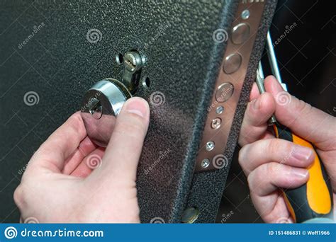 Image of a person applying pressure to a screwdriver inserted in a door lock mechanism