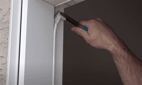 Image of a person inserting a coat hanger through the gap between the door frame and weatherstripping