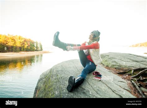 Young woman pulling off her riding boots using a bootjack Stock Photo, Royalty Free Image