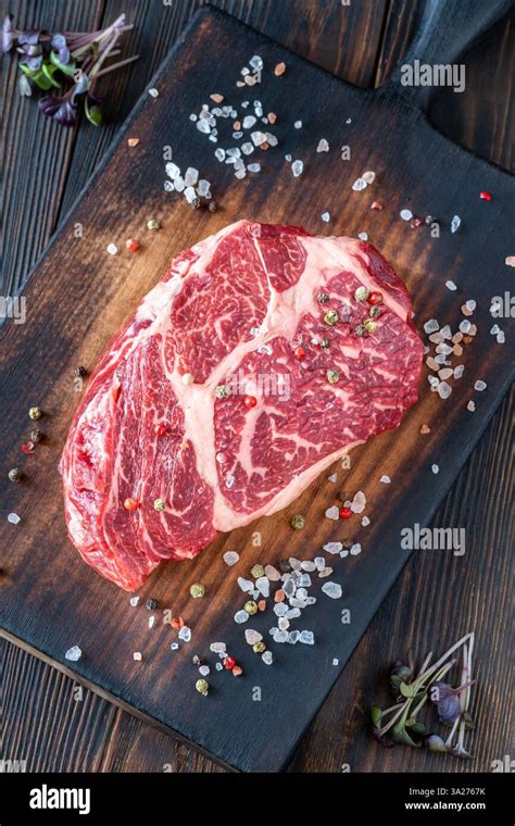 A perfectly cooked ribeye steak, resting peacefully on a cutting board, its juices patiently redistributing throughout the meat.