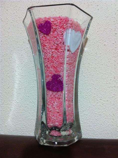 Vase filled with dyed rice and glittered hearts for valentines day. To