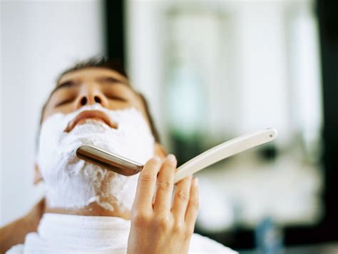 Barber shaves customer with straight razor blade, man's haircut and