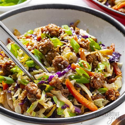 a bowl filled with rice, carrots and celery next to green onions