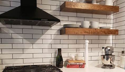 Open floating shelves in white kitchen with white bevelled subway tile