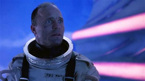 A person standing in a dark room, head in hands, looking distressed