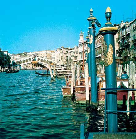 Gondolas gliding through Venice's canals, with ornate bridges and colorful buildings in the background.