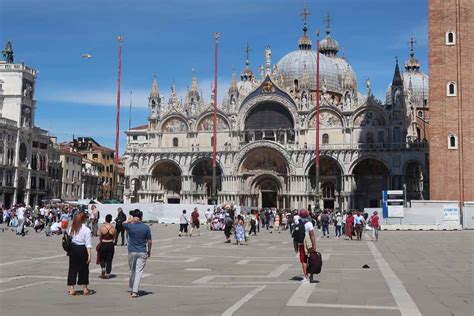 Image of St. Mark's Square, showcasing the iconic Doge's Palace with its intricate architecture, St. Mark's Basilica, and the Campanile rising in the background, people enjoying the vibrant atmosphere in the square