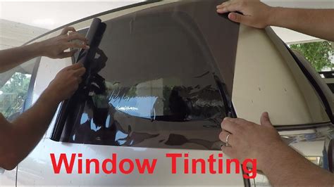 Image of a person applying window tint to a window, demonstrating DIY installation.