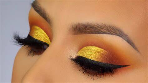 A woman demonstrating a yellow and blue eye makeup look